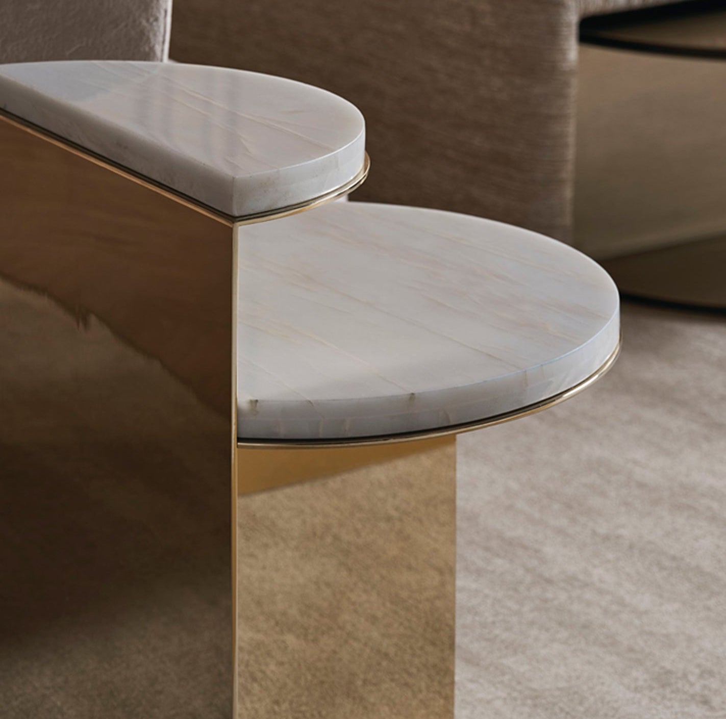 Small round marble table with gold base against a neutral background